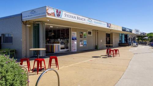 a group of red stools in front of a store at Stylish Unit With Water Views in Bellara