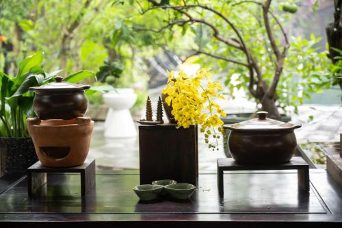 two vases and bowls on a table with plants at Amazing Ninh Binh Garden in Xuân Sơn