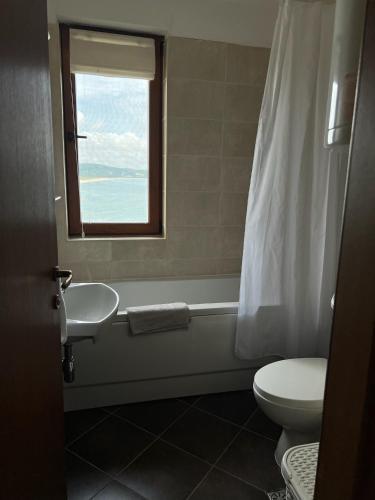 a bathroom with a toilet and a sink and a window at Saint Thomas Holiday Village Condo in Sozopol