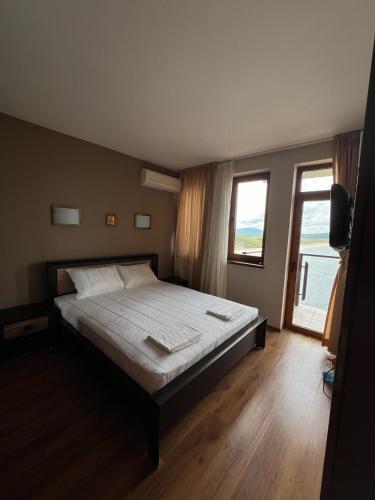 a bedroom with a large bed and a large window at Saint Thomas Holiday Village Condo in Sozopol