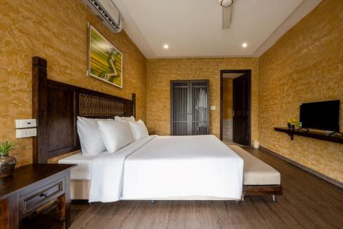 a bedroom with a large white bed and a tv at Amazing Ninh Binh Garden in Xuân Sơn