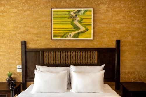 a bed with white pillows and a picture on the wall at Amazing Ninh Binh Garden in Xuân Sơn