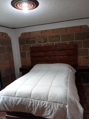 a bedroom with a white bed with a brick wall at Hotel familiar los Fresnos in Santiago Oxtempan