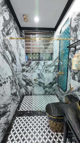 a bathroom with a shower with a black and white tile floor at Happy Tam Coc Ecolodge in Ninh Binh