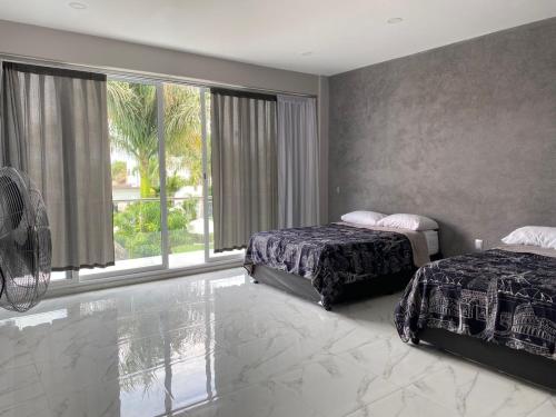 a bedroom with two beds and a large window at Hotel Arcangeles in Los Limones