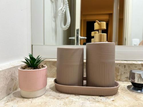 two vases sitting on a counter in front of a mirror at TOP quarto Stay Inn hotel 3 min Av Paulista in Sao Paulo