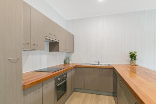 a kitchen with a wooden counter top and a sink at The Sailfish Suite - Beachside Granny Flat by uHoliday in Kingscliff