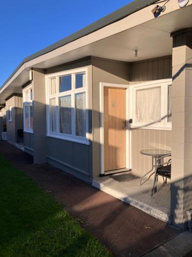 a small house with a patio and a table at Trentham Motel in Upper Hutt