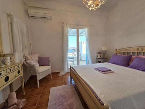 a bedroom with a bed and a chair and a window at Phaedra Villa Kythnos in Kithnos