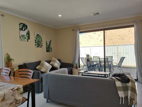 a living room with a couch and a table at 5-bedroom 2 bath stylish retreat near beach and wineries in Christie Downs,newly upgraded google TV with Neflix,chromecast, Apple TV, Amazon prime video in Christies Beach