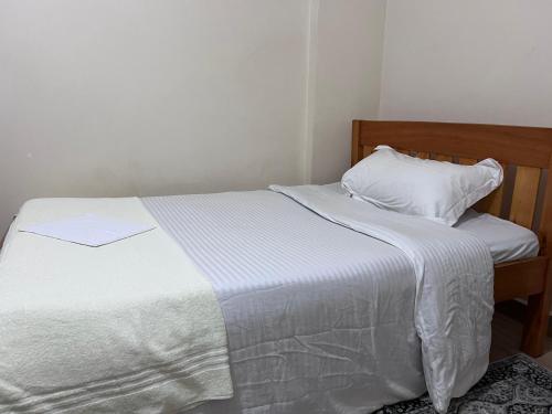a bed with a white blanket and a pillow at The Skyline Loft in Juja