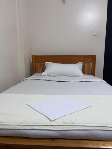 a bed with white sheets and a white pillow at The Skyline Loft in Juja
