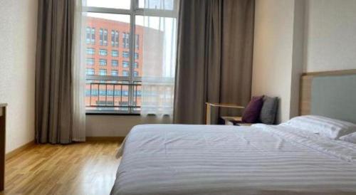 a hotel room with a bed and a large window at 7Days Inn Tianjin Airport NO.1 Bridge Branch in Tianjin