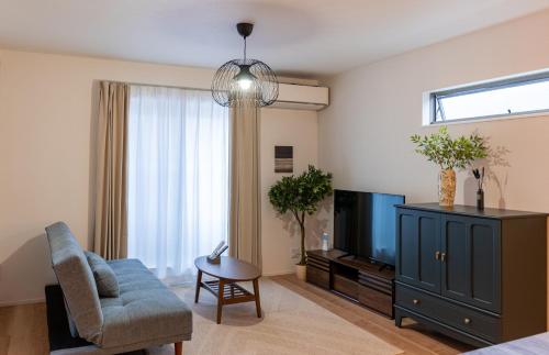 a living room with a tv and a couch and a chair at New open 旅タイム 桃谷MOMO in Osaka