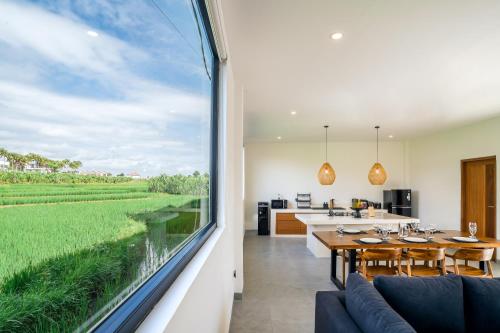 a kitchen and dining room with a large window at Villa Onetti - Luxury Villa with Private Pool, Rooftop & Rice Field Views in Tumbak Bayuh