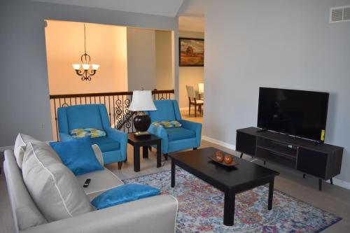 a living room with two blue chairs and a tv at Cozy 3BR-3BA Home Near Zona Rosa Shopping and Dining in Kansas City
