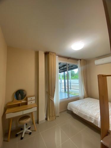 a bedroom with a bed and a desk and a window at FUJI Hotel in Nakhon Ratchasima
