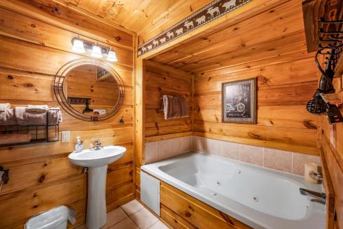 een badkamer met een bad en een wastafel en een ligbad bij Peaceful Pines Cabin-patio with hot tub for small families or couples in Gatlinburg