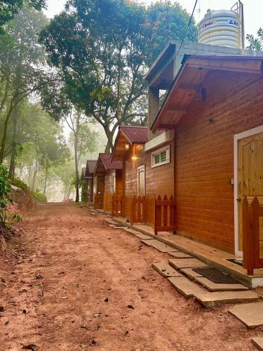 a row of wooden houses on a dirt road at Coorg Jungle Mist in Madikeri