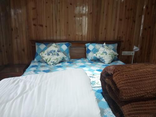 a bed with blue and white pillows in a bedroom at Ganga Homestay in Darjeeling