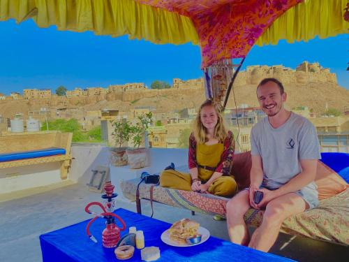 Un hombre y una mujer sentados en una cama frente a un castillo. en Jaisalmer Murad Haveli, en Jaisalmer