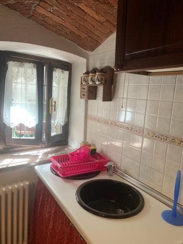 a kitchen sink with a pink tray on a counter at Mary Home in Limone Piemonte