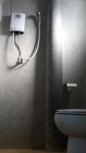 a bathroom with a toilet and a hose on the wall at บ้านพักคุณยายเขียว in Ban Thung Kham