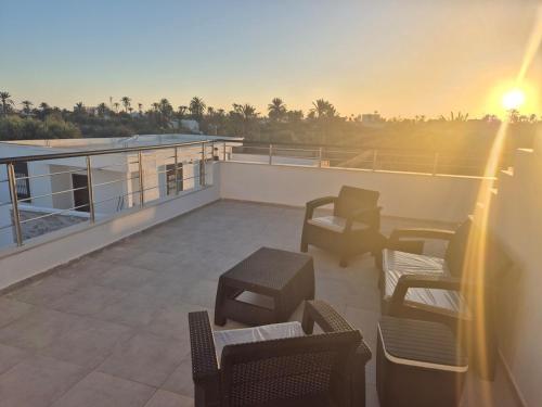 a balcony with chairs and tables on a roof at Villa Dalissa avec piscine chauffée in Awlād ‘Umar