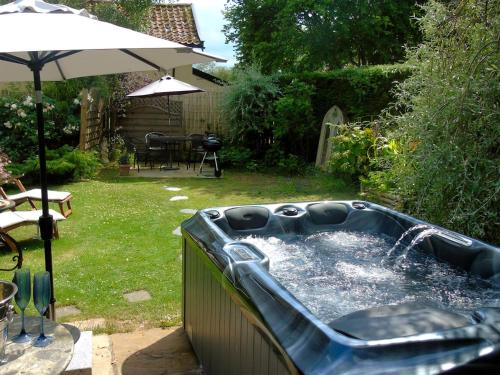 a hot tub in a yard with an umbrella at The Coach House - Ukc2365 in Watton
