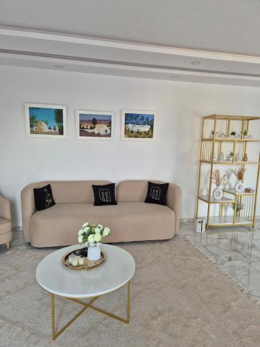 a living room with a couch and a table at Villa Dalissa avec piscine chauffée in Awlād ‘Umar