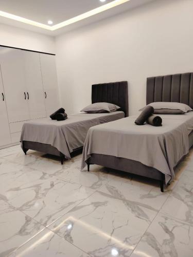 two beds in a room with marble floors at Villa Dalissa avec piscine chauffée in Awlād ‘Umar