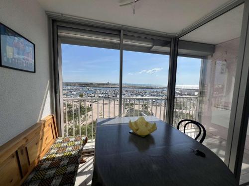 une salle à manger avec une table et une grande fenêtre dans l'établissement Studio cabine, vue port, 4 pers, à 100m de la plage - FR-1-701-95, à Valras-Plage