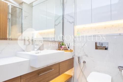 Bloomfields Deluxe Studio In Azizi Riviera في دبي: حمام أبيض مع حوض ومرآة