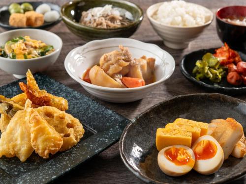 a table with plates of food and bowls of food at HOTEL MYSTAYS Ueno Iriyaguchi in Tokyo