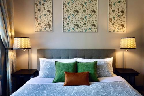 a bedroom with a bed with green pillows and two lamps at Oaktown Roost in Oakland