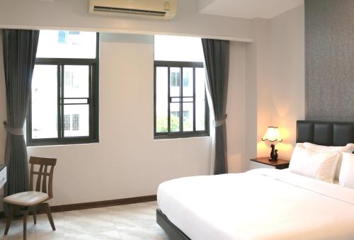 a bedroom with a white bed and three windows at Urbanite Hotel in Vientiane