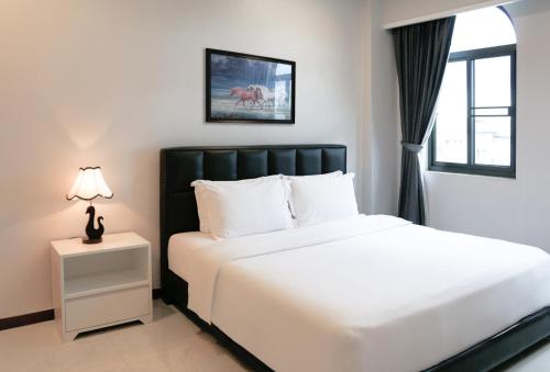 a bedroom with a large white bed and a window at Urbanite Hotel in Vientiane