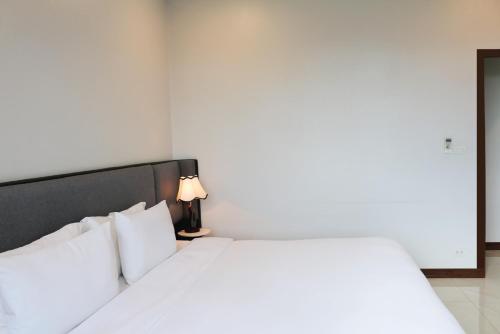 a bedroom with a large white bed with a lamp at Urbanite Hotel in Vientiane