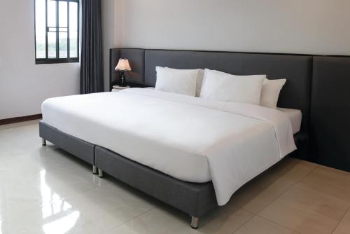 a large bed with white sheets and pillows in a room at Urbanite Hotel in Vientiane