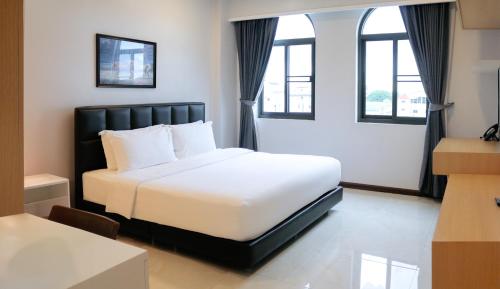 a hotel room with a white bed and windows at Urbanite Hotel in Vientiane
