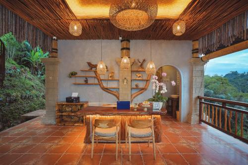 a dining room with a table and chairs on a balcony at Harsa Sanctuary by GenuineHost in Ubud