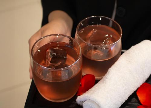 a person holding two wine glasses on a tray at Urbanite Hotel in Vientiane