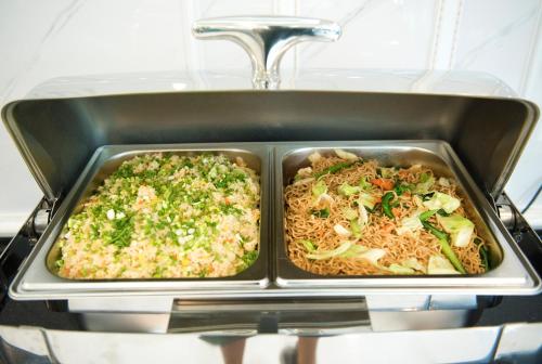 two trays of food in a pan on a stove at Urbanite Hotel in Vientiane