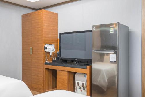 a room with a tv on a desk with a refrigerator at Zenith Hotel in Guri