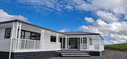 une maison blanche avec une terrasse couverte et des escaliers dans l'établissement Pleasant View Lodge, à Tauwhare