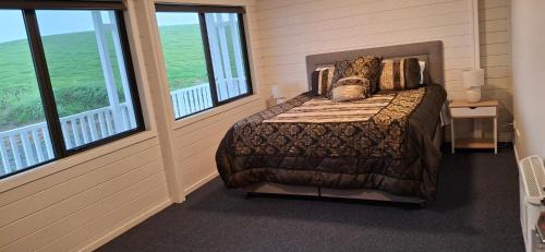 une chambre avec un lit dans une pièce avec des fenêtres dans l'établissement Pleasant View Lodge, à Tauwhare