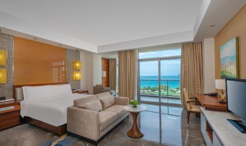 a bedroom with a bed and a couch and a television at MGM Grand Sanya in Sanya