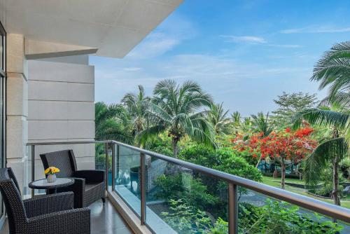 a balcony with chairs and a view of palm trees at MGM Grand Sanya in Sanya