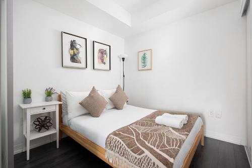 a white bedroom with a bed and a night stand at Classy and Luxury 2 bedroom apartment 5 mins to Dundas Square in Toronto
