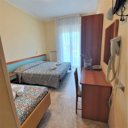 a hotel room with two beds and a desk and a desk at Hotel De La Plage in Rimini
